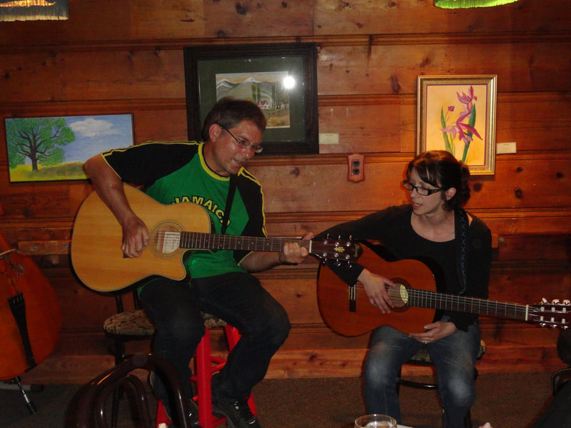 Two people seated playing guitar